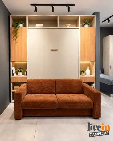 Letto a scomparsa Magic chiuso con divano davanti e colonne con vani a giorno, nello showroom Livein Camerette Mugnano
